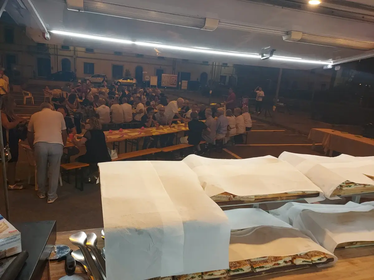 La tavolata vista dal banco del camion, di sera, con le teglie coperte in primo piano