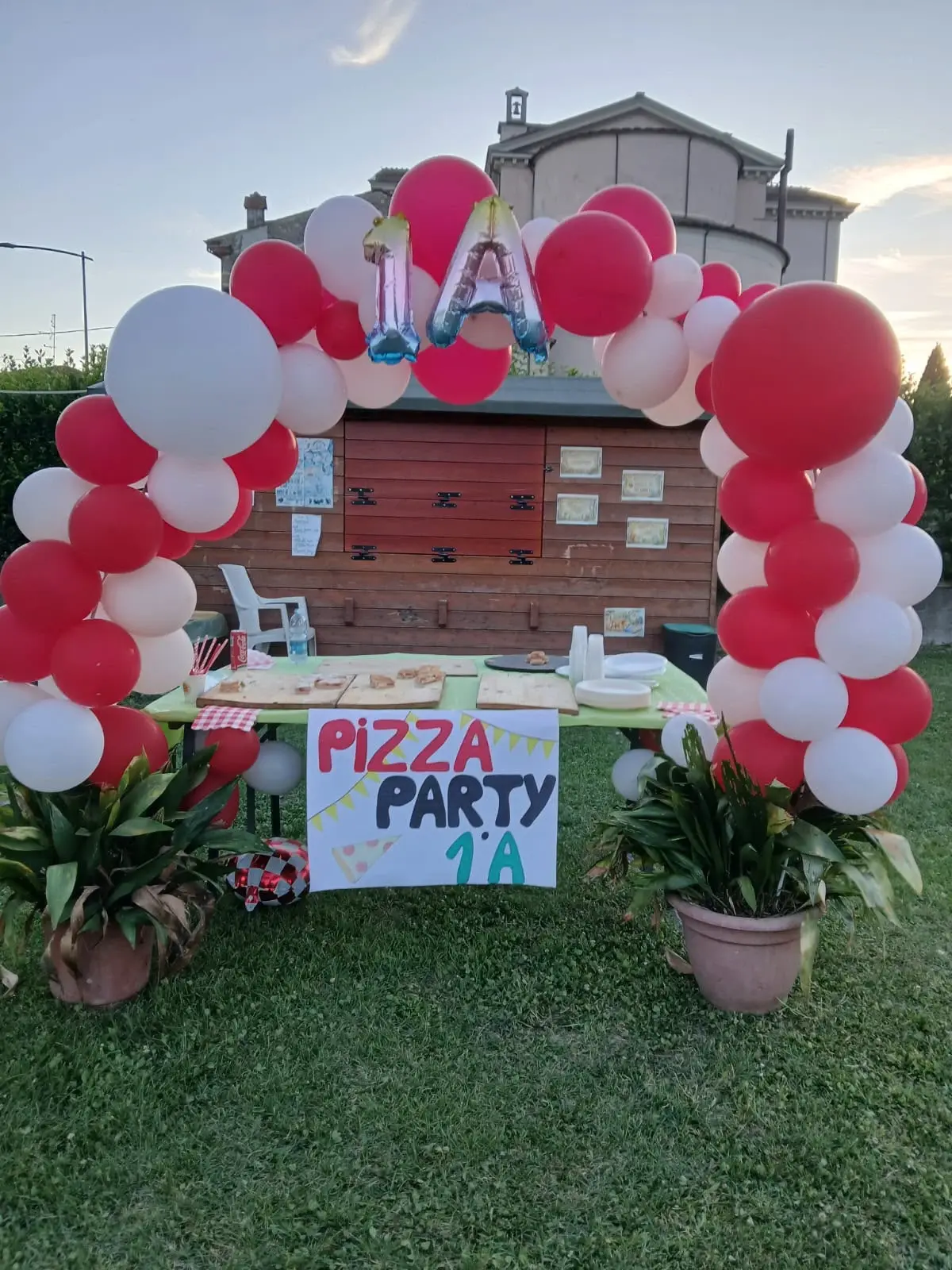 Arco di palloncini bianchi e rossi con il cartello di una festa di compleanno