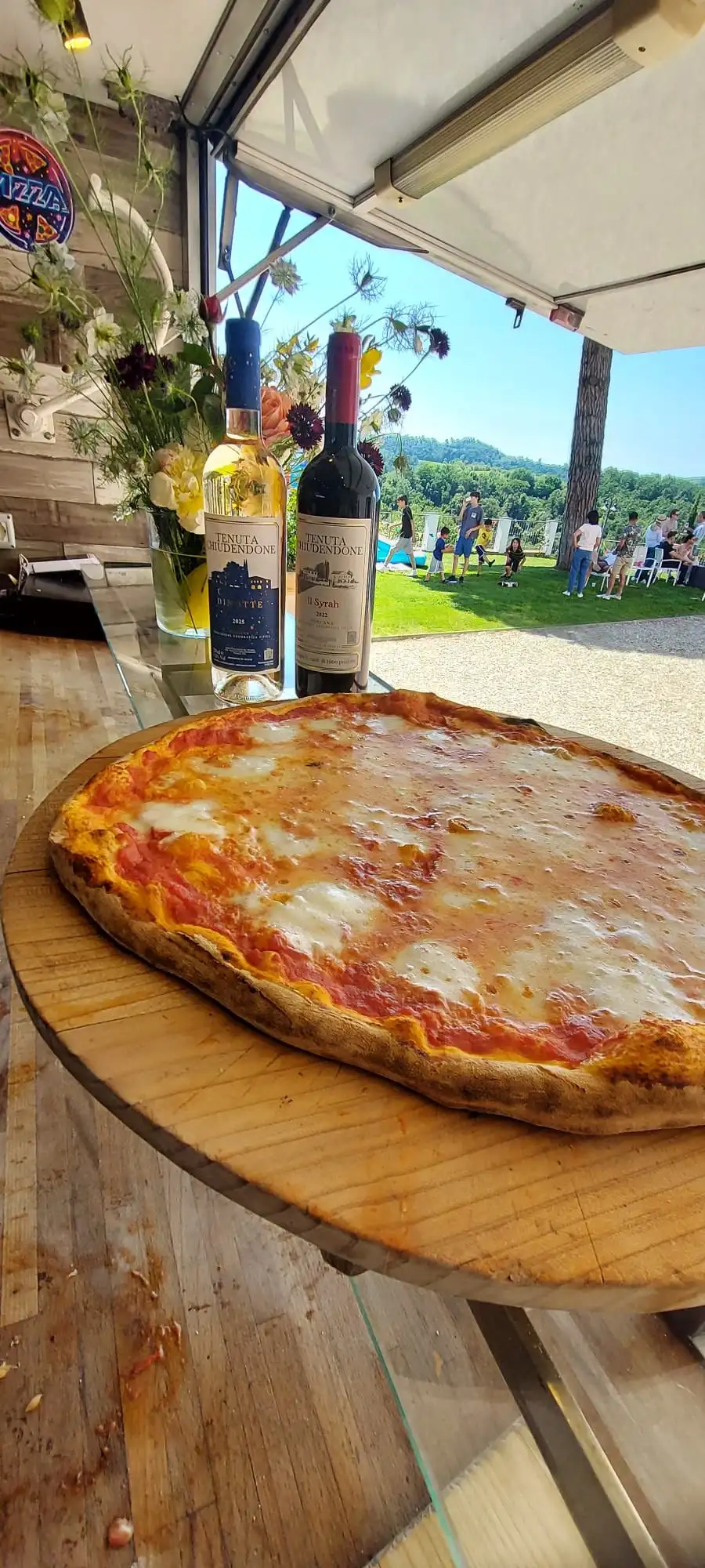 Una margherita sul tagliere, accanto alle bottiglie di vino