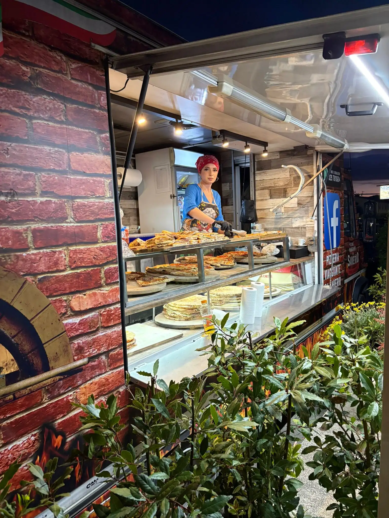Il banco con le pizze in mostra e il forno alle spalle