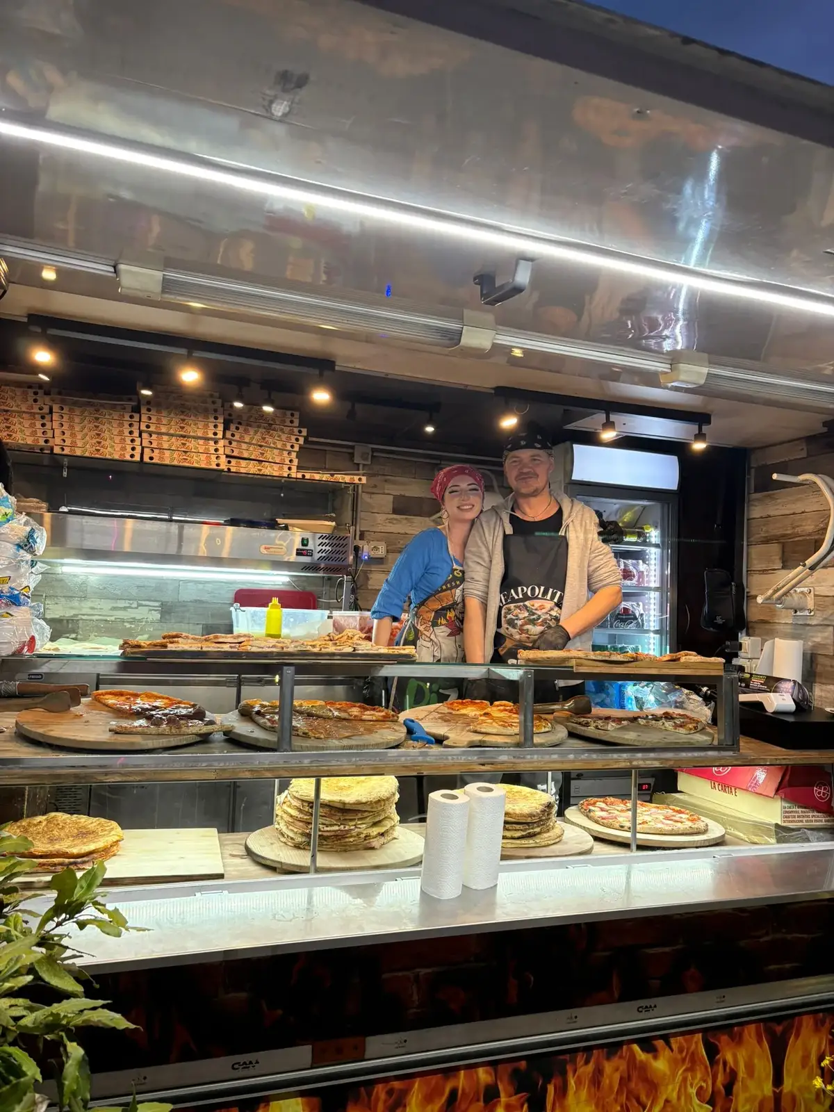 Due pizzaioli dietro al banco carico di pizze e schiacciate