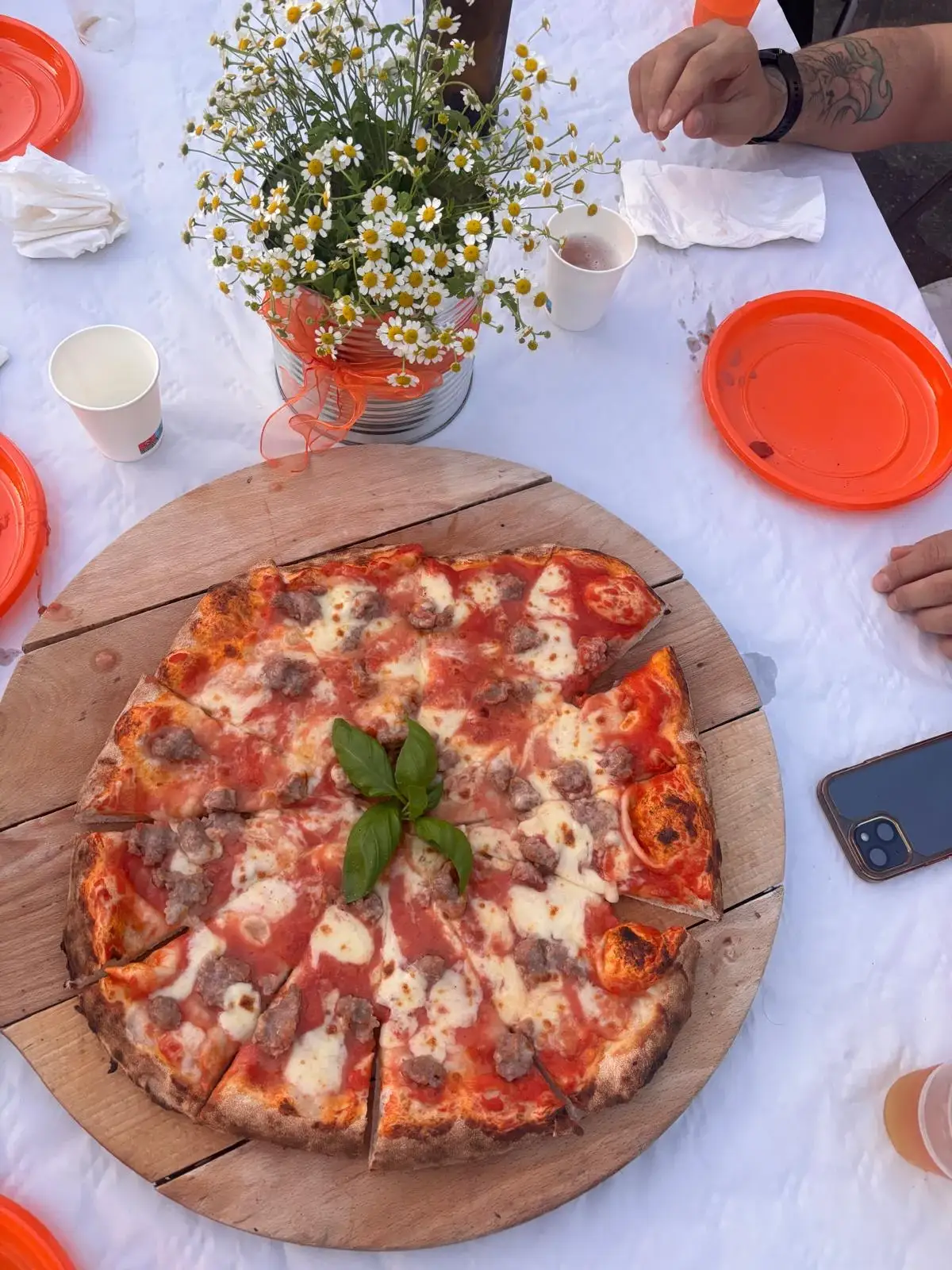 Una pizza su una tavola apparecchiata, con i fiori di campo