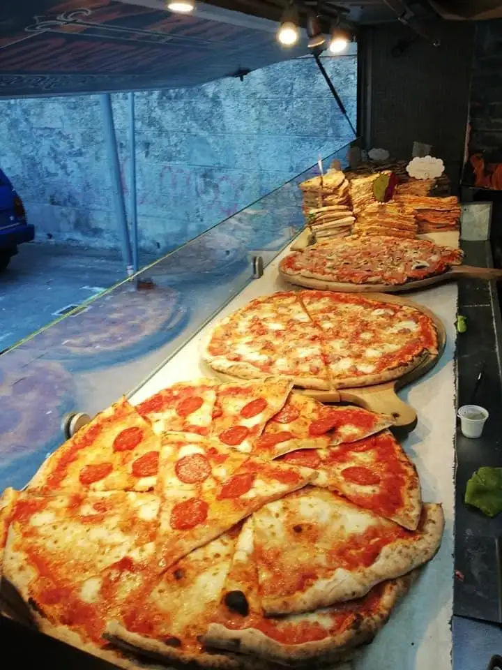 Il banco pieno di pizze, con il forno acceso dietro