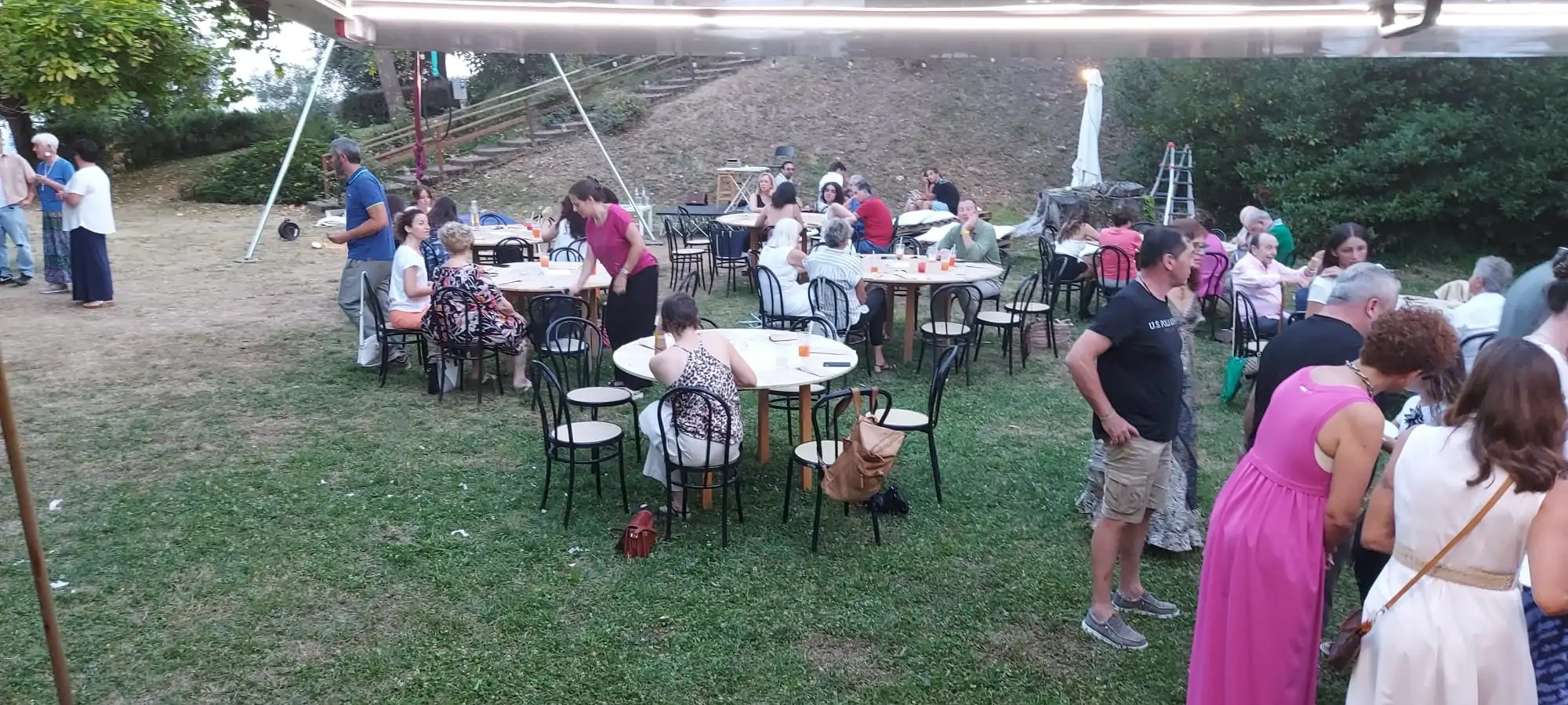 Tavolini rotondi all’aperto, con gli ospiti seduti, verso sera