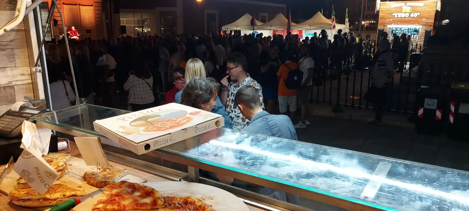 La folla a un evento, con le pizze sul banco