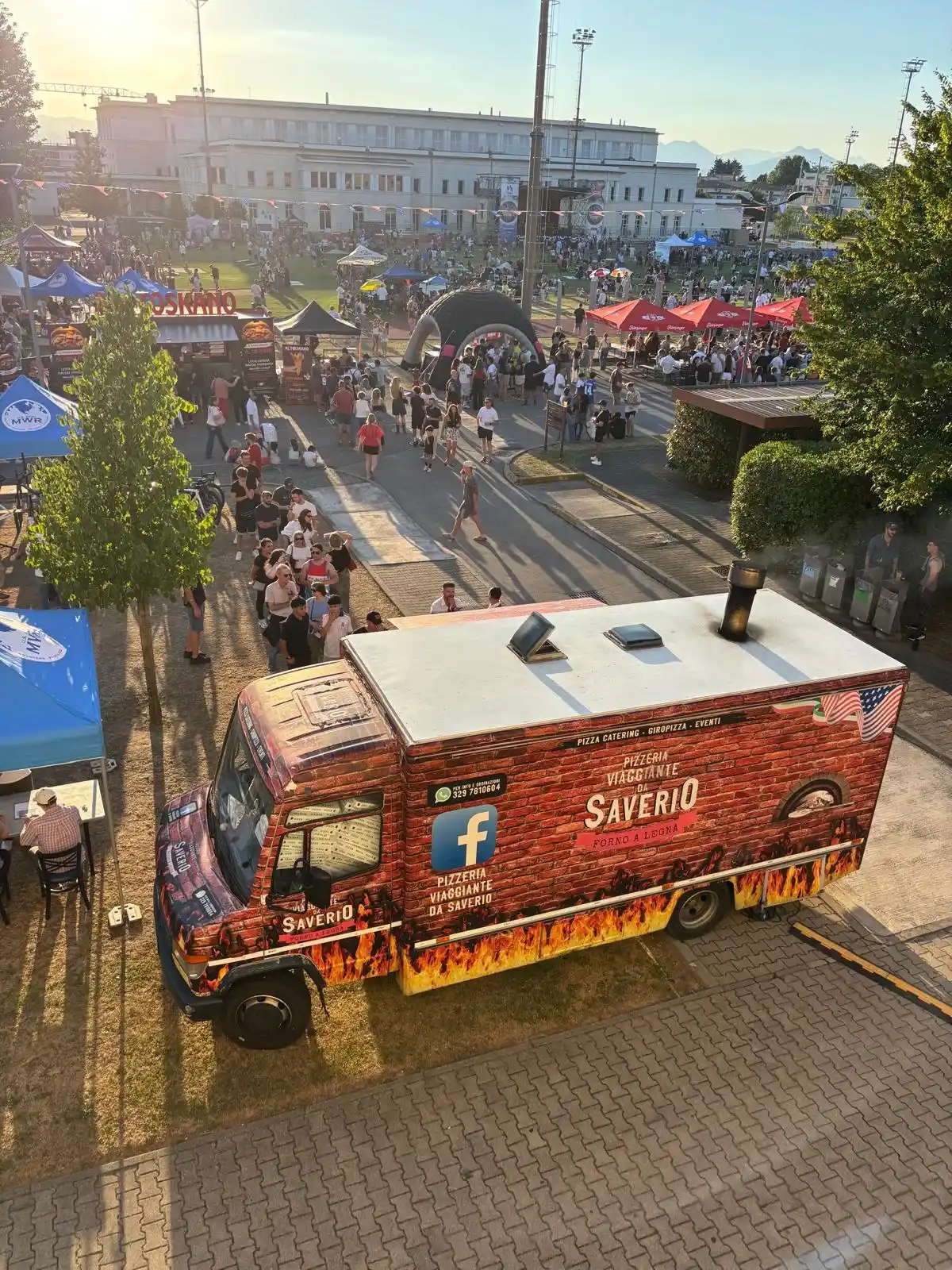 Il camion visto dall’alto al tramonto, con la fila di persone che gli gira intorno e la piazza piena